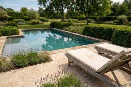 Piscine enterrée intégrée dans un jardin élégant avec margelles en travertin et haies taillées